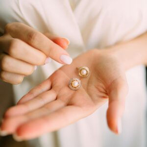 Close-up of elegant pearl earrings held in a hand, showcasing luxury jewelry.